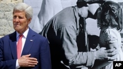 U.S. Secretary of State John Kerry stands near a photo by Tony Vaccaro, whose name graces the town hall of Saint-Briac-sur-Mer, France, June 7, 2014.