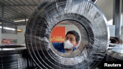 贵州省贵阳市一名戴着口罩的工人在缆线生产线上工作。（2020年2月25日）