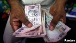 A private money trader counts Indian rupee currency notes at a shop in Mumbai, India.