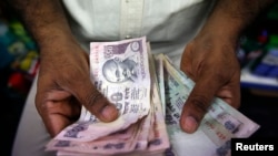 FILE - A private money trader counts Indian rupee currency notes at a shop in Mumbai, India.