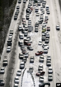 En esta fotografía aérea del 29 de enero de 2014, los autos salen en la I-75 en dirección norte cerca del paso elevado del río Chattahoochee; se amontonan en la mediana de la interestatal cubierta de hielo después de una tormenta de nieve invernal, en Atlanta.