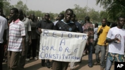 Wani mutumi rike da kwalin da aka rubuta "A koma ga aiki da tsarin mulki" a jiki a lokacin zanga-zangar nuna kin jinin juyin mulkin da sojoji suka yi, Litinin 26 Maris 2012 a Bamako, babban birnin Mali.