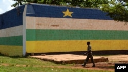 FILE - A man walks in front of the jail of Bangui, "Maison Centrale de Ngaragba," whose walls are painted with the colors of the flag of Central African Republic, April 22, 2014. 