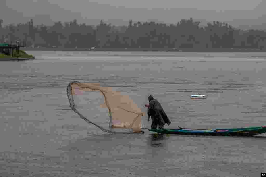 A Kashmiri fisherman casts his net as it rains at the Dal Lake on the outskirts of Srinagar, Indian-controlled Kashmir.