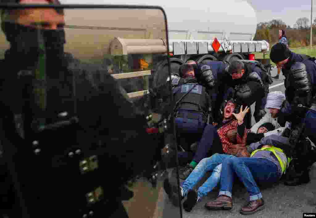 French gendarmes evacuate demonstrators who sit on the road and block full tanker trucks in front of the French oil giant Total refinery in Donges.