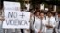 A student holds up a sign reading "no more violence" in Spanish, during a protest against presidential re-election, in Asuncion, Paraguay, April 3, 2017.