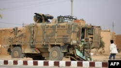 A Turkish soldier stands near his armored vehicle on a highway near the northern Syrian town of Ain Issa in the Raqqa region, on Nov. 26, 2019, as Turkey-backed forces deploy reinforcements around the town.