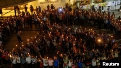 People hold candles as they form a peace sign during an anti-violence campaign in center of Bangkok, Thailand, Jan. 3, 2014.