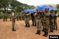 FILE - Malian and MINUSMA troops carry the flag-draped coffins of two U.N. peacekeepers killed in a bomb attack in Kidal, during their funeral in Bamako, Dec. 18, 2013.