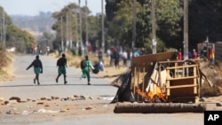 FILE: Schoolchildren run past a burning barricade, following a job boycott called via social media platforms, in Harare, Wednesday, July,6, 2016. 