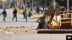 Schoolchildren run past a burning barricade, following a job boycott called via social media platforms, in Harare, Wednesday, July,6, 2016. (AP Photo/Tsvangirayi Mukwazhi)