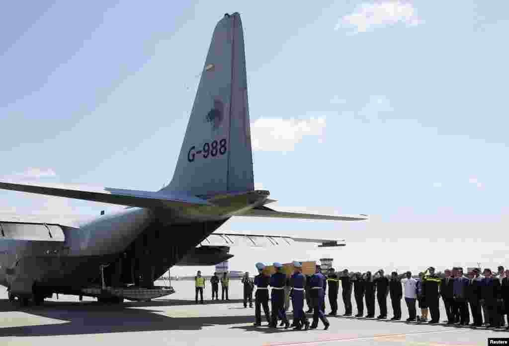 Honor guards carry a coffin of one of the victims of Malaysia Airlines MH17 before loading it on a transport plane heading to the Netherlands, at Kharkiv Airport, July 23, 2014.&nbsp;