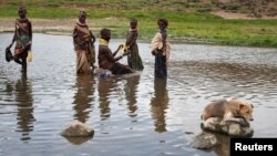 FILE - A Turkana woman and children bathe in a hot spring pool in northwestern Kenya inside the Turkana region of the Ilemy Triangle, Sept. 26, 2014.