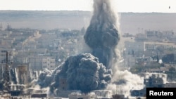 An explosion from an air-strike is seen in the Syrian town of Kobani from the town of Suruc, Turkey, Oct. 29, 2014. 