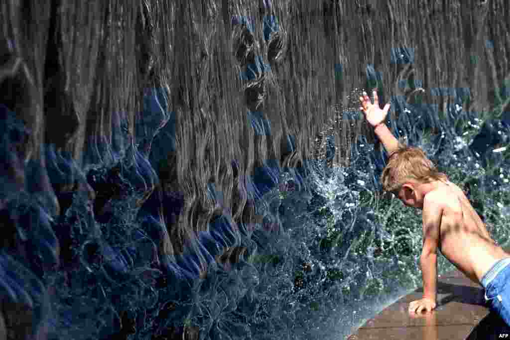 A boy cools himself in a fountain just outside Kremlin in Moscow, Russia.