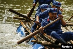 Participants race on a raft across a lake during a Communist team-building course extolling the spirit of the Long March, organized by the Revolutionary Tradition College, outside Jinggangshan, Jiangxi province, China, Sept. 14, 2017.