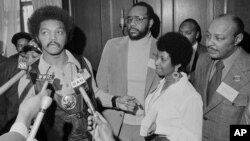 FILE - The Rev. Jesse Jackson speaks to reporters at the Operation PUSH Soul Picnic in New York, March 26, 1972, as Tom Todd, vice president of PUSH, from second left, Aretha Franklin and Louis Stokes look on.