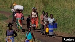 FILE - Women walk to a camp for the displaced in the aftermath of Cyclone Idai, in John Segredo, near Beira, Mozambique, April 3, 2019. 