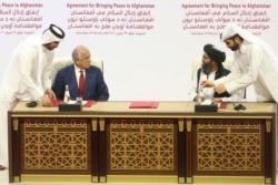 FILE - In this Feb. 29, 2020, photo, U.S. peace envoy Zalmay Khalilzad, left, and Mullah Abdul Ghani Baradar, the Taliban group's top political leader, sign a peace agreement between Taliban and U.S. officials in Doha, Qatar.