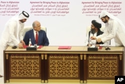 In this Feb. 29, 2020 file photo, U.S. peace envoy Zalmay Khalilzad, left, and Mullah Abdul Ghani Baradar, the Taliban group's top political leader sign a peace agreement between Taliban and U.S. officials in Doha, Qatar.