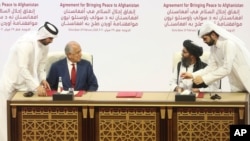 FILE - In this Feb. 29, 2020 file photo, U.S. peace envoy Zalmay Khalilzad, left, and Mullah Abdul Ghani Baradar, the Taliban group's top political leader sign a peace agreement between Taliban and U.S. officials in Doha, Qatar. 