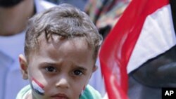 A woman carries a child during a demonstration in Tahrir Square in Cairo May 20, 2011