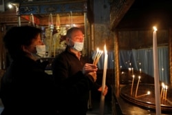 Visitors light candles in the Church of the Nativity, amid the coronavirus disease (COVID-19) outbreak, in Bethlehem in the Israeli-occupied West Bank November 26, 2020. (REUTERS/Mussa Qawasma)