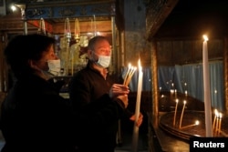 Visitors light candles in the Church of the Nativity, amid the coronavirus disease (COVID-19) outbreak, in Bethlehem in the Israeli-occupied West Bank November 26, 2020. (REUTERS/Mussa Qawasma)