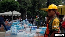 A soldier stands guard next to donations of bottled water for rescue workers and victims next to a collapsed building after earthquake in Mexico City, Mexico, Sept. 20, 2017. 