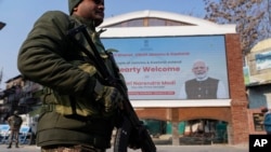 An Indian paramilitary soldier patrols near an electronic display in Srinagar, welcoming the Indian Prime Minister Narendra Modi to inaugurate a strategic tunnel project that connects Kashmir with Ladakh, Jan.13, 2025.