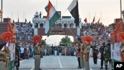 FILE- Indian and Pakistani flags are lowered during a daily retreat ceremony at the India-Pakistan joint border check post of Attari-Wagah near Amritsar, India, July 21, 2015.