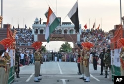 FILE- Indian and Pakistani flags are lowered during a daily retreat ceremony at the India-Pakistan joint border check post of Attari-Wagah near Amritsar, India, July 21, 2015.