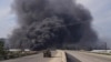 Smoke rises while members of the Syrian forces ride on a vehicle as they battle against a nascent insurgency by fighters from ousted leader Bashar al-Assad's Alawite sect, in Latakia, Syria March 7, 2025. 