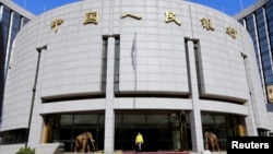 FILE - A woman walks out of the headquarters of the People's Bank of China (PBOC), the central bank, in Beijing.