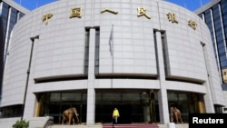 FILE - A woman walks out of the headquarters of the People's Bank of China (PBOC), the central bank, in Beijing.