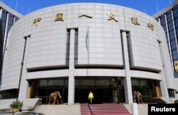 FILE - A woman walks out of the headquarters of the People's Bank of China (PBOC), the central bank, in Beijing.