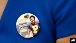Hua Qu, the wife of Xiyue Wang, a student being held at an Iranian prison, wears a button bearing his picture as she speaks at a news conference to mark the third anniversary of his imprisonment, Aug. 8, 2019, at the National Press Club in Washington.