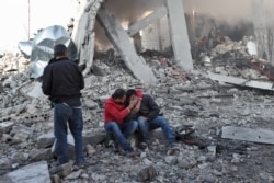 A Syrian man comforts another on the rubble of a building after a reported Russian airstrike on a popular market in the village of Balyun in Syria's northwestern Idlib province, Dec, 7, 2019.