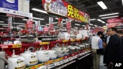 FILE - Chinese customers look at rice cookers in Tokyo's Akihabara electronics district, March 25, 2010. The Chinese government's push to transform itself into a consumer driven economy encourages the production of better consumer appliances.