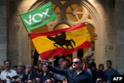 FILE - A man waves a Spanish flag with the silhouette of the spanish medieval nobleman and military leader Rodrigo Diaz de Vivar "El Cid", during a campaign rally of far-right party Vox, in Burgos, ahead of general elections.