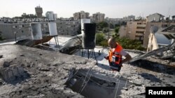 Seorang anggota Tim SAR tengah memeriksa sebuah atap bangunan yang hancur akibat serangan roket di kota Ashkelon, Israel (Foto: dok). Polisi Israel mengatakan telah menemukan sisa-sisa roket dekat kota Ashkelon, di selatan Israel, Selasa (26/2).