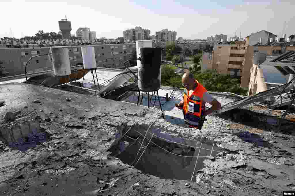 Petugas penyelamat Israel memeriksa atap sebuah gedung yang rusak karena roket di kota pantai Ashkelon (18/11). (Reuters)