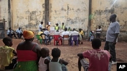 Local residents watch as ballots are counted at an outdoor polling station in Bissau, Guinea-Bissau, March 18, 2012. 