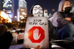 A protester holds a sign reading "Stop Tear Gas" during a rally against the police's use of tear gas in Hong Kong, Friday, Dec. 6, 2019.