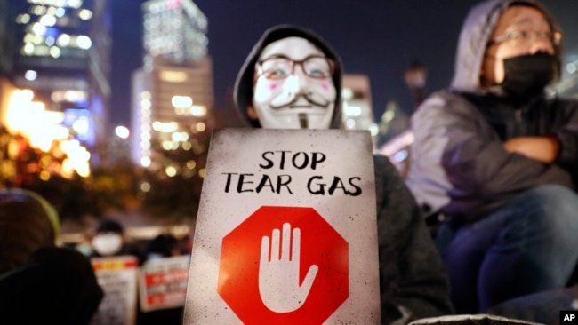 一名香港示威者手举标语牌抗议港警使用催泪弹。（2019年12月6日）