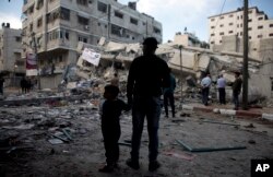 Palestinians stand in front of a destroyed multi-story building was hit by Israeli airstrikes in Gaza City, May 5, 2019.