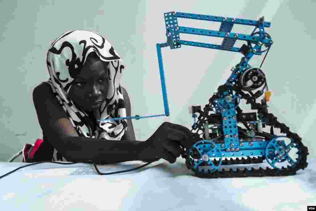 Rokyaha Cisse, 17, from Dakar, adjusts her team's robot at the 2017 Pan-African Robotics Competition in Dakar, Senegal, May 19, 2017. Their robot sends sounds into the ground, which detect the presence of metal. (R. Shryock/VOA)
