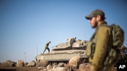 FILE - Israeli soldiers gather next to their tanks near the border with Syria in the Israeli-controlled Golan Heights, Nov. 28, 2016. 