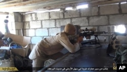 FILE - This file picture released on July 13, 2015 by the Rased News Network, a Facebook page affiliated with Islamic State militants, shows an Islamic State militant sniper in position during a battle against Syrian government forces, in Deir el-Zour province, Syria.