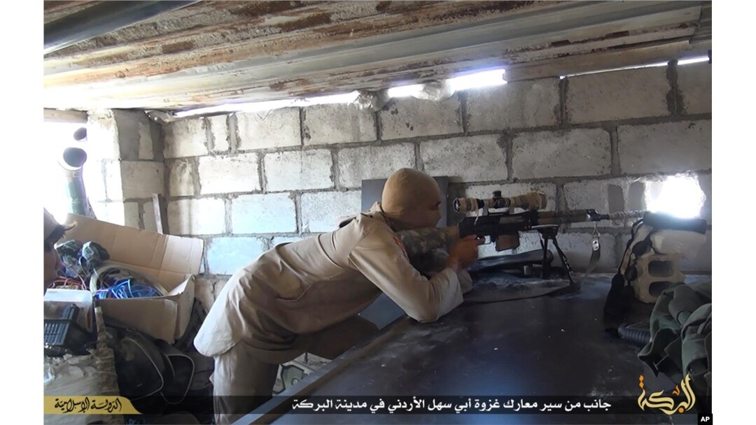 FILE - This file picture released on July 13, 2015 by the Rased News Network, a Facebook page affiliated with Islamic State militants, shows an Islamic State militant sniper in position during a battle against Syrian government forces, in Deir el-Zour pro